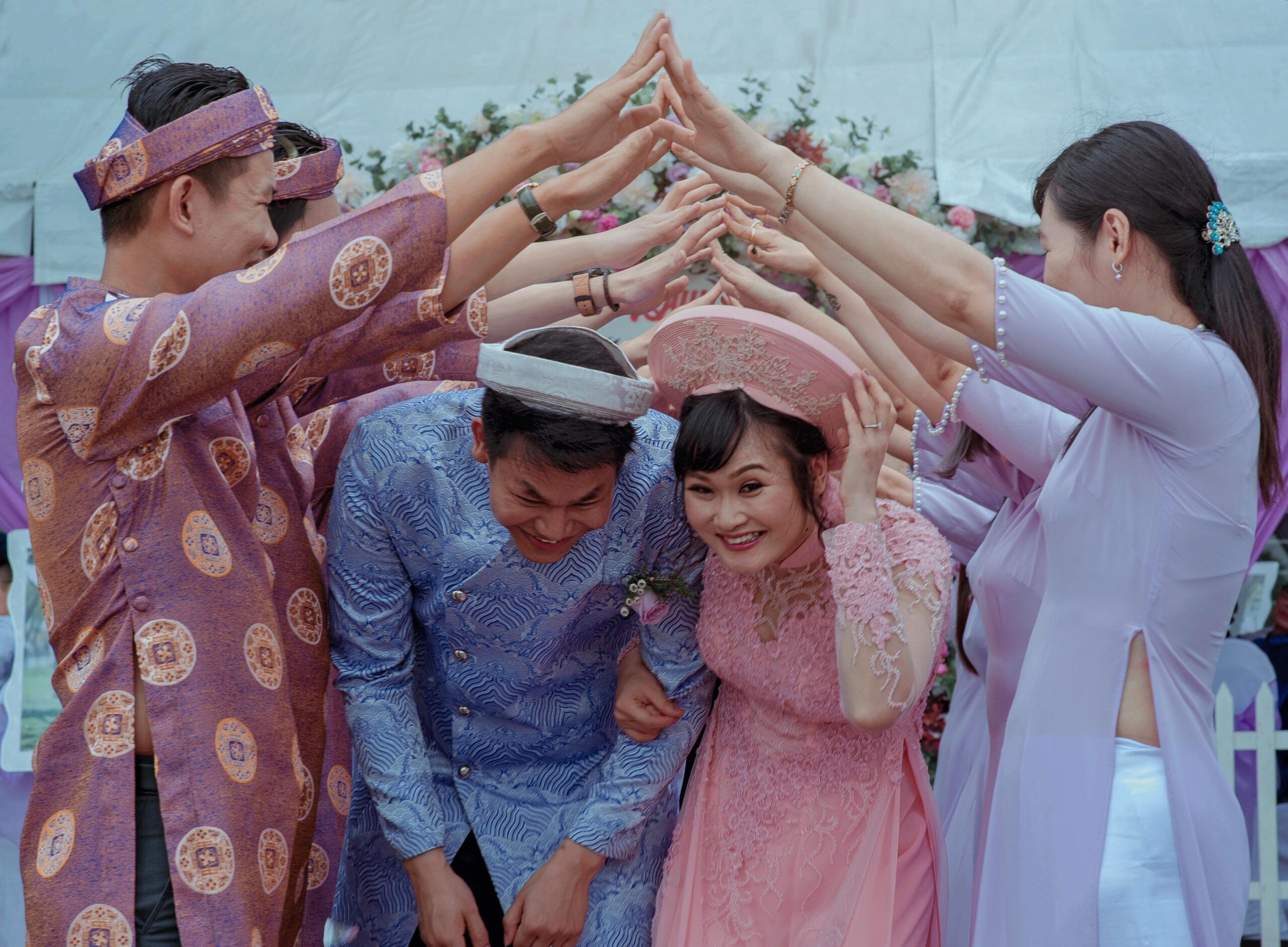 pexels-photo-758898-758898 Happy Vietnamese couple celebrates their wedding with friends in traditional attire outdoors.